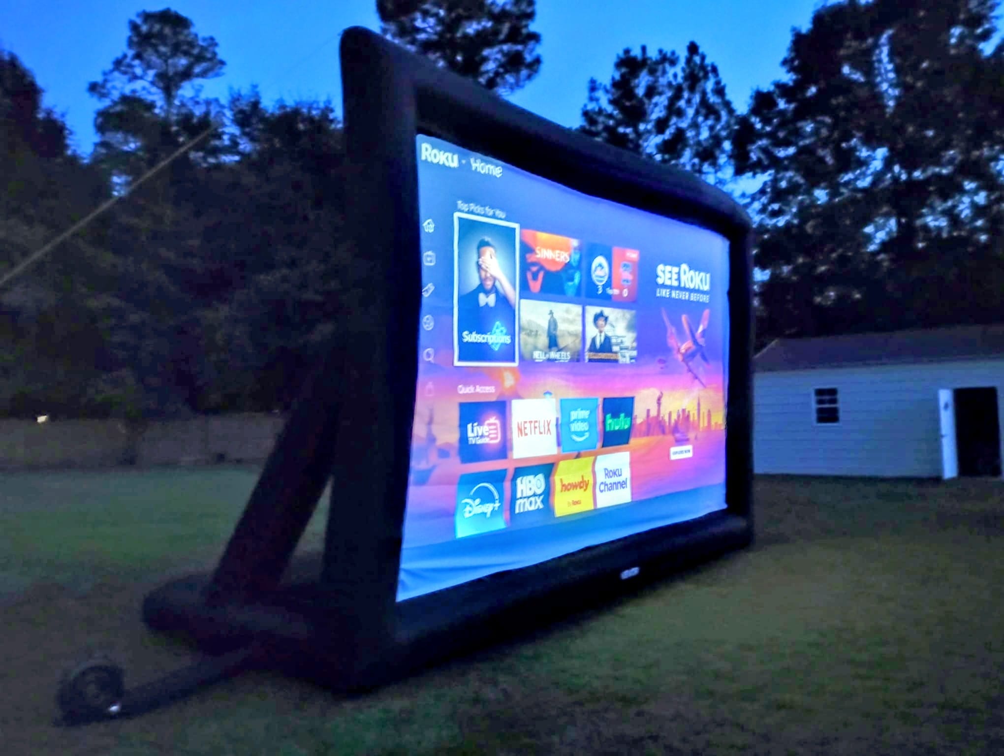 Inflatable movie screen glowing in a backyard